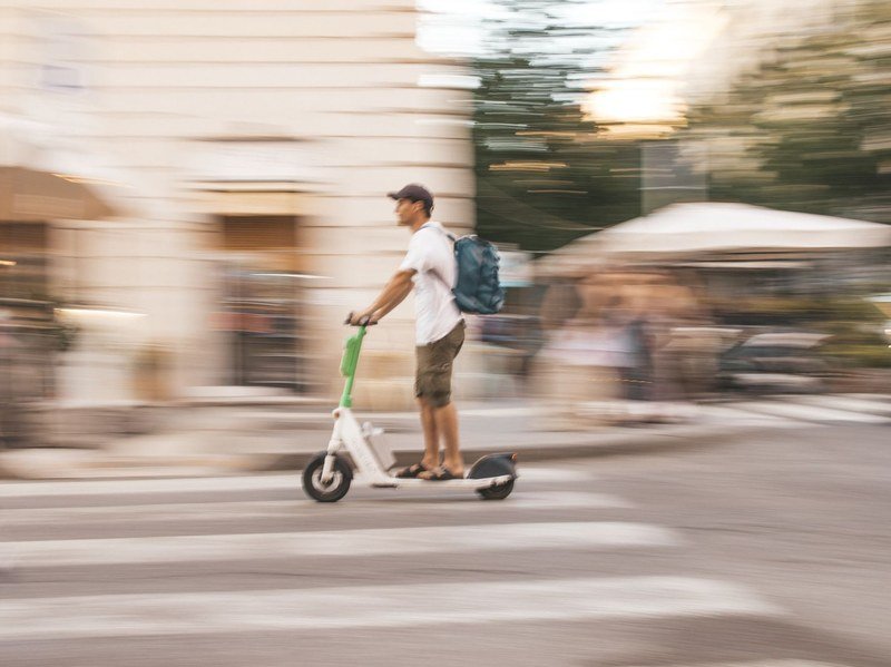 Rider on an electric scooter crossing a city street